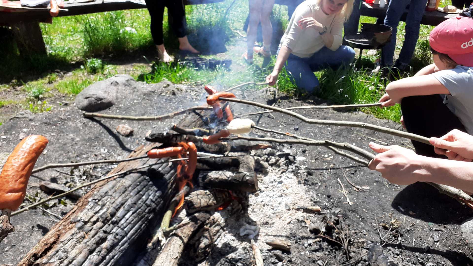 Dzieci przy ognisku pieczące kiełbaski