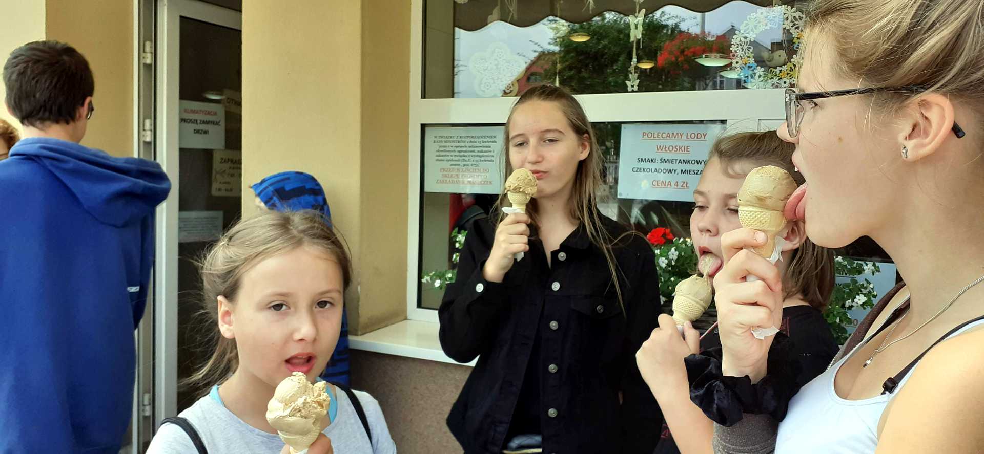 Dzieci jedzą lody przy cukierni